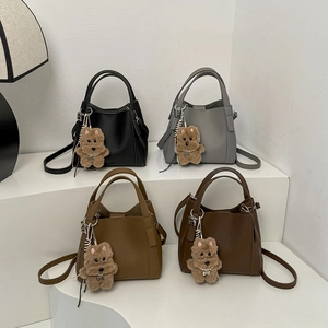 Detail view of stylish bucket bags in four colors with cute dog charms and leather straps