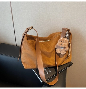 Detailed shot of brown faux suede hobo bag with wide shoulder strap and cute dog charm
