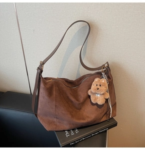 Close-up of dark coffee suede hobo bag with adjustable strap and cute bear charm