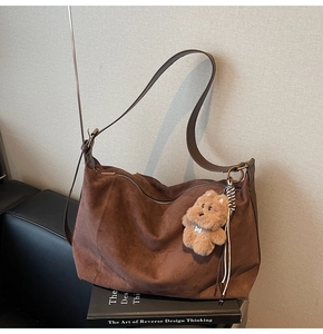 Brown suede tote bag detail featuring vintage gold hardware and a cute teddy bear charm