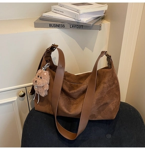 Detail of dark brown suede crossbody bag with fluffy dog charm and metal zipper