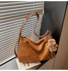 Detail of a large brown suede tote bag with metal zipper and cute plush dog charm