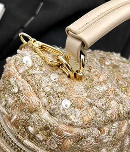 Dettaglio della chiusura dorata e del cinturino in pelle beige sulla borsa in tweed