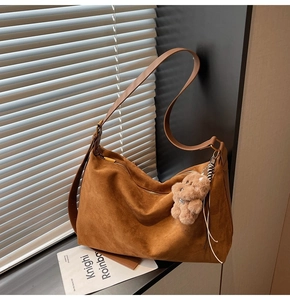 Brown suede hobo shoulder bag featuring a cute plush bear pendant and metal zipper detail