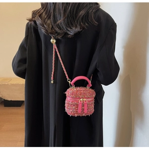 Close-up of pink tweed mini box bag with chain strap on a black coat back view