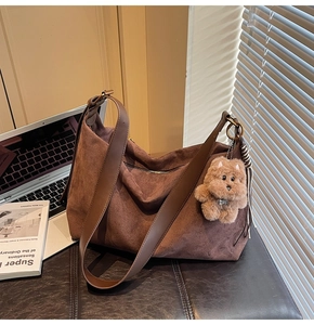 Detail view of large brown faux suede crossbody bag with cute plush puppy charm