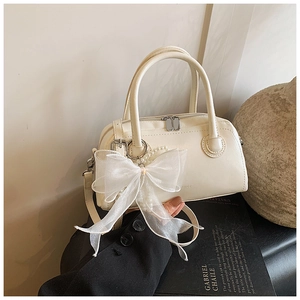 Détail du sac polochon blanc cassé avec nœud en organza et charme de perles blanches