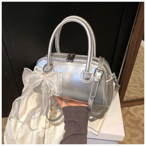 Détail du sac Boston argenté avec nœud en organza, perle et texture métallisée