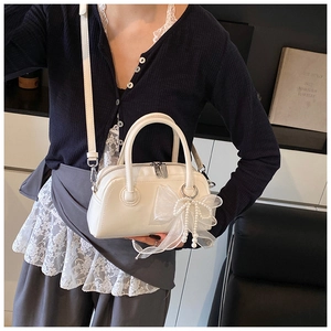 Détail du sac oreiller en similicuir blanc crème avec nœud en organza et breloque en perles