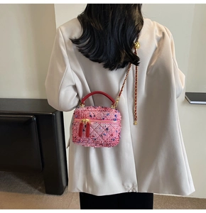 Detail of pink tweed quilted mini bag with golden ball chain and red leather handle