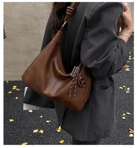 Detail of retro brown leather shoulder bag with knot strap on woman in grey blazer