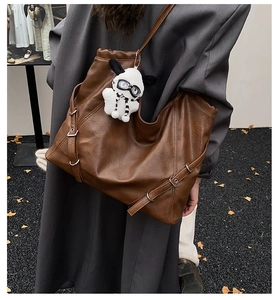 Detail of dark brown faux leather tote bag featuring metal buckles and cute puppy charm