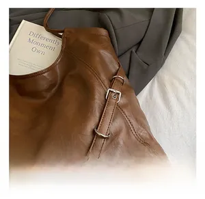 Detailed close-up of dark brown tote bag featuring shiny leather texture and silver buckle strap