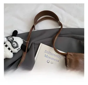 Detail shot of brown leather tote bag dual handles with soft litchi grain texture