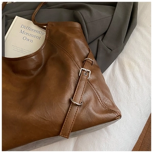 Detail view of brown leather tote bag with silver buckle and premium leather texture