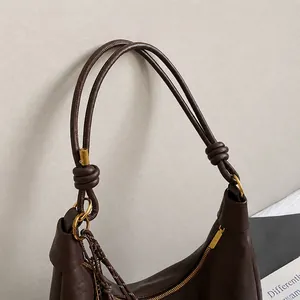 Detail of dark brown leather tote bag showing knotted handle and gold metal hardware