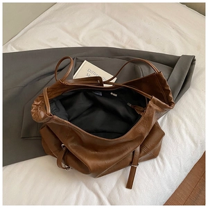 Detail view of large brown retro tote bag showing black lining and interior zipper pocket