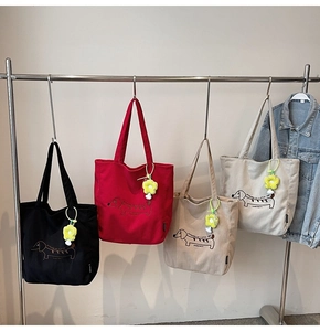 Detalle de cuatro bolsos tote de pana en negro, rojo, marrón y gris con bordado de perro