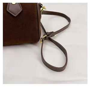 Detail of adjustable strap and golden hardware on dark brown suede pillow bag