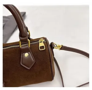 Detail view of the smooth golden zipper and brown suede texture on this minimalist pillow bag