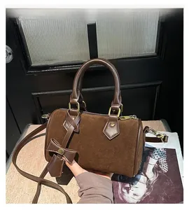 Detail of dark brown suede boston bag with leather trim and golden hardware