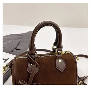 Detail view of brown suede pillow bag with comfortable handle and gold hardware accents