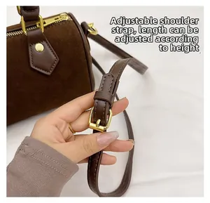 Detail view of adjustable shoulder strap and gold buckle on brown suede pillow bag