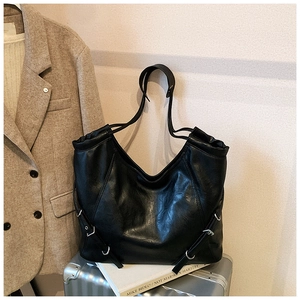 Detail of black leather tote bag featuring a V-shaped side opening and silver buckle