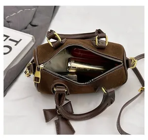 Detail view of brown suede Boston bag interior showing space for cosmetics and gold zipper