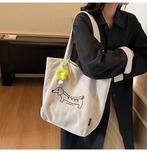 Detalle del bolso tote de pana con bordado de perro salchicha y colgante de girasol