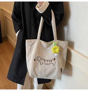 Detalle de bolsa tote de pana con perro bordado y colgante de flor de peluche