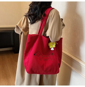 Detalle de bolso tote de pana roja con bordado de perro y colgante de flor amarilla