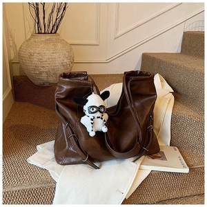 Retro dark brown leather tote bag with plush dog charm on beige stairs