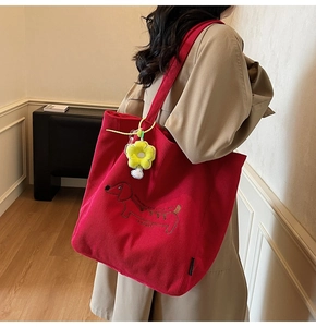 Detalle del bolso tote de pana roja con bordado de perro salchicha y dije de flor