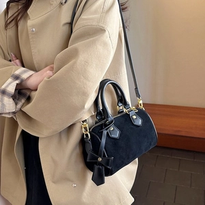 Elegant black suede cylinder handbag for women featuring a golden bow pendant and handles