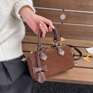 Dark brown suede Boston pillow bag for women with leather bow charm and autumn outdoor vibes