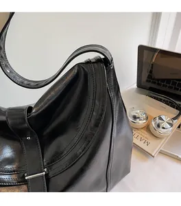 Detail of glossy black PU leather shoulder bag with wide strap and silver buckle