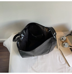 Interior view of black glossy leather tote bag showing magnetic closure and inner pocket
