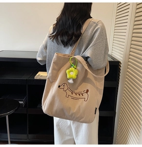 Detalle del bolso tote de pana beige con bordado de teckel y colgante de flor amarilla