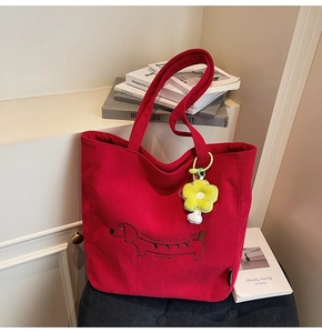 Detalle del bolso tote de pana roja con bordado de perro salchicha y colgante de flor