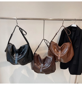 Three classic leather shoulder bags in black, coffee, and caramel colors on a display rack