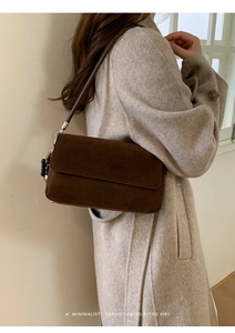 Detail of a dark brown suede shoulder bag with bead charms on a wool coat outfit