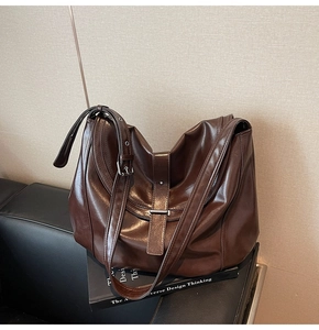 Detail of a dark brown leather saddle bag with adjustable buckle strap and vintage finish