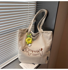 Detalle del bolso tote de pana beige con bordado de perro salchicha y colgante girasol