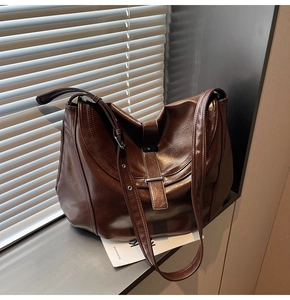 Detailed shot of brown vintage saddle bag featuring glossy faux leather and buckle strap