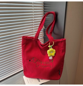 Detalle del bolso tote de pana roja con bordado de perro salchicha y colgante floral