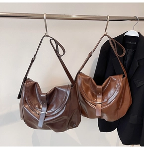 Detail view of vintage brown PU leather saddle bags hanging on a rack with a blazer