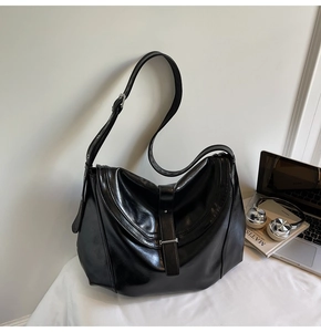 Polished black mirror finish hobo bag with silver buckle detail in a lifestyle setting