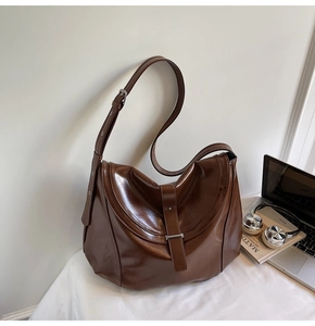 Detail of vintage brown glossy leather shoulder bag with adjustable strap and metal buckle
