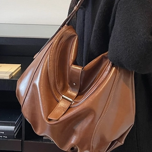 Brown leather minimalist hobo bag with adjustable strap shown in a lifestyle shoulder view